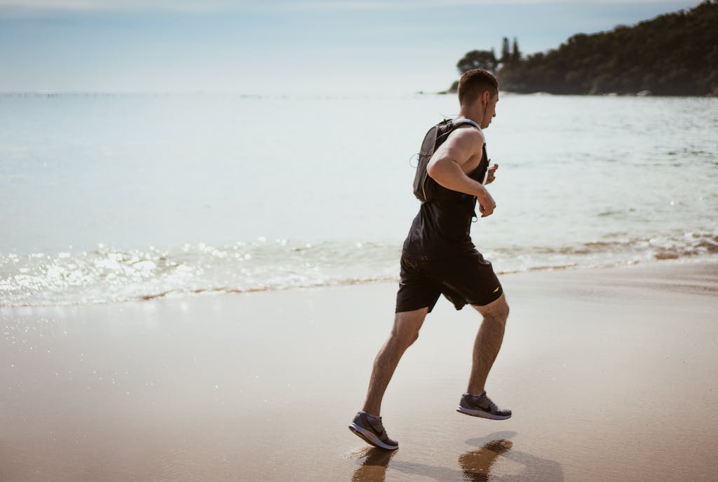 Man running along the beach enjoying fitness and freedom by the ocean waves.